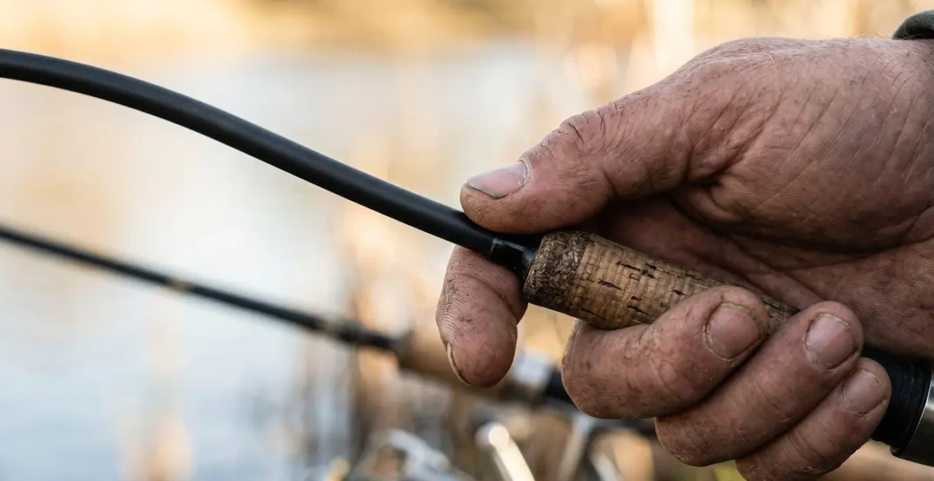 Gros plan sur une main tenant une canne à pêche démontrant le point d'équilibre ergonomique